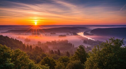 Golden sunrise over misty forested hills and winding road landscape