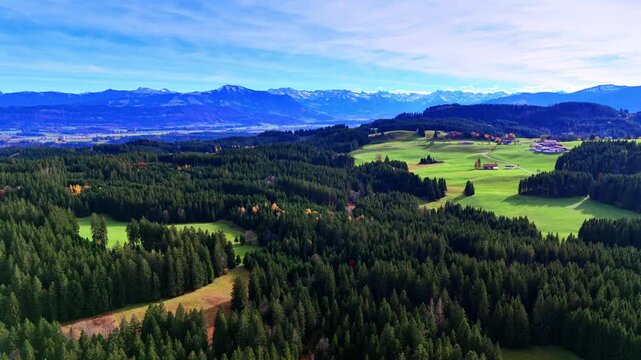 Alpine foothills forest view. Aerial view of German foothills with dark forests and distant Alps.