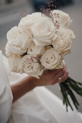 Elegant white rose bouquet held gently with a soft backdrop during a wedding celebration