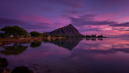 Dramatic purple sunset over a calm ocean reflecting a majestic mountain and shoreline