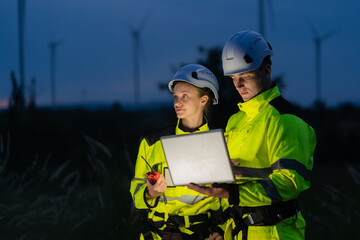 Energy engineers on the farm during dusk can monitor data and computerized power generation systems to support sustainable clean energy development.