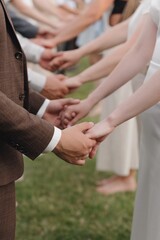 Couples holding hands during a ceremony on a sunny day in a park setting with green grass