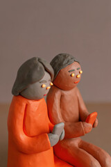 Valentine's clay, Clay couple sitting back to back, connected by hearts, enjoying their phones in cozy atmosphere
