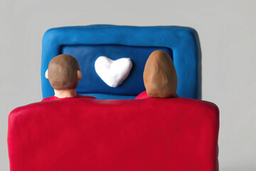 Valentine's clay, Clay couple watching movie together on sofa with heart on screen, expressing love and connection