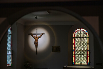 Inside Basilique Notre-Dame-de-Buglose, light casts a dramatic glow on a wooden crucifix and beautiful stained glass windows. This quiet moment captures the essence of peace and reflection.