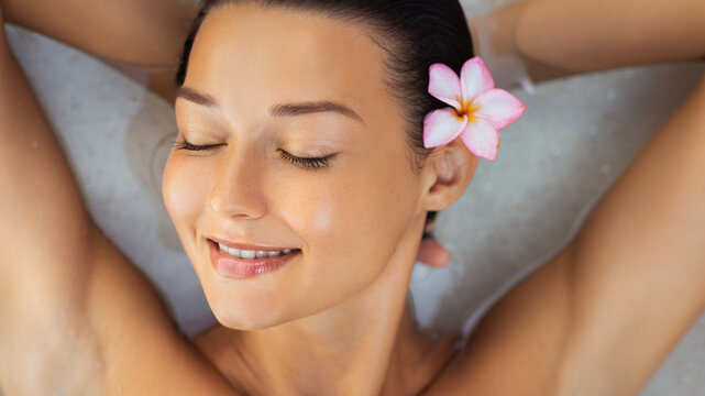 Smiling Woman Relaxing In Spa Bath With Tropical Flower Wellness Concept