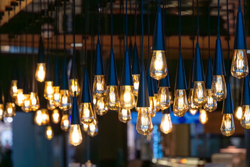 Lots of decorative soft light bulbs hanging from the ceiling in a dark room.