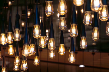 Lots of decorative soft light bulbs hanging from the ceiling in a dark room.