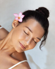 Fototapeta premium Close-Up of Asian Woman With Flower Relaxing in Spa With Eyes Closed