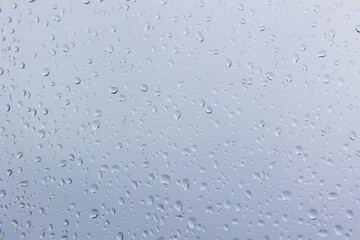 Raindrops on glass in sharp detail with a blurred, pale cloudy sky outside, perfect for moody, minimal, and natural ambiance visuals.