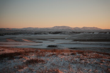 Obraz premium Minimalist winter landscape with mountains at sunset. Snow-covered peaks under soft golden light, peaceful and serene atmosphere. Perfect for nature, travel, and scenic photography.