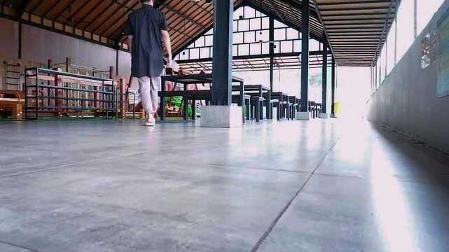 Barefoot person walking through an empty outdoor cafe with tables and chairs in daylight