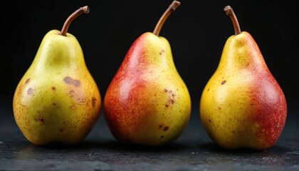 Close up photo shows three pears in a row. Fruits are ripe with yellow and red tones. Bruises and spots are visible on the skin against black background.