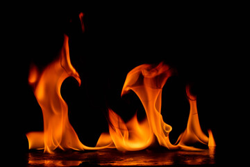 Intense red-orange flames curling and twisting against dark black background, showcasing the...