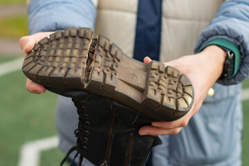Torn Boot. A man holds an old boot in his hands.