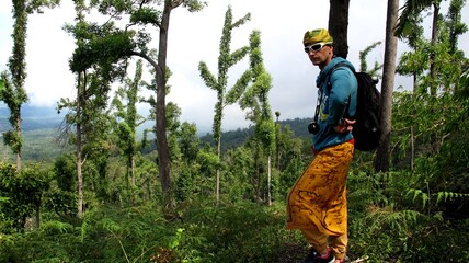 The guy stands against the background of a tropical forest. Adventures in Southeast Asia