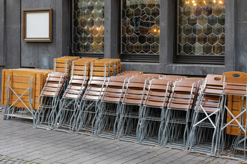 Stacked outdoor wooden chairs await patrons, a hint of ambiance in the windows.