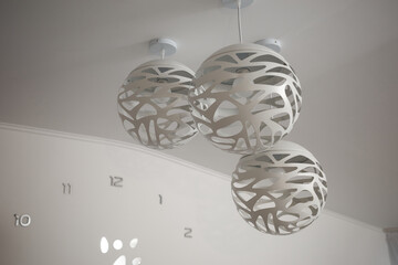 Modern decorative pendant lights hang from the ceiling in a stylish interior space with a minimalist design and soft lighting