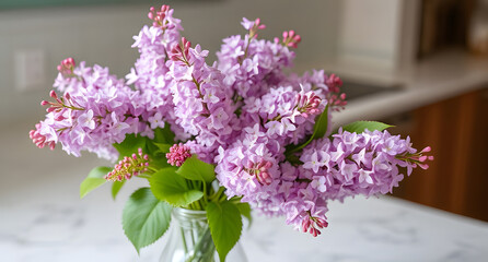 Radiant bouquet of lilac sprigs in glass vase, on marble countertop