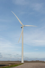 A wind turbine stands tall against a blue sky, harnessing renewable energy.