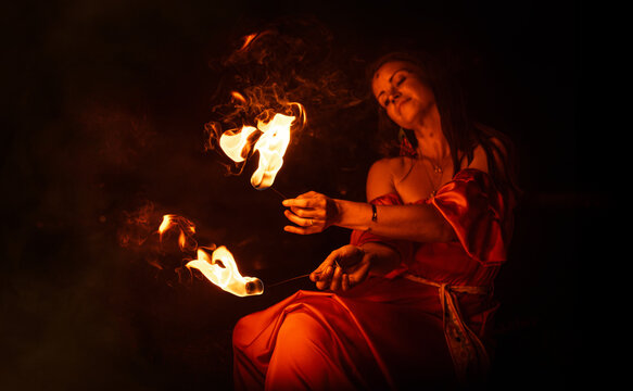 An enchanting fire dancer beautifully showcases her talent with mesmerizing flames during a performance.