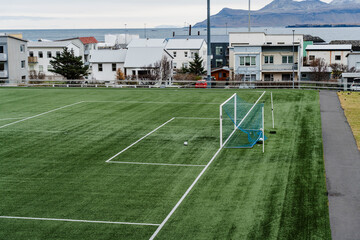 Obraz premium A soccer field is set against a backdrop of buildings and distant mountains.