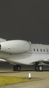 white unmarked business jet parked apron fbo gat stands heavy highlighted during night airport panning shot private aircraft area scene 