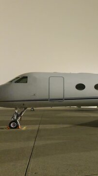 white heavy business jet designed for haul travel parked apron fbo gat stands during dark night luxurious connection to long panning shot long-haul aircraft 