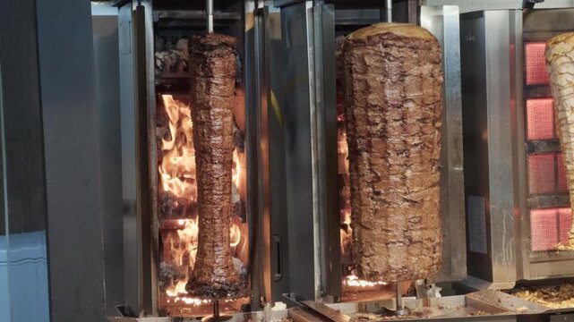Close-up rotating doner kebab meat grilling on vertical rotisserie in a restaurant kitchen
