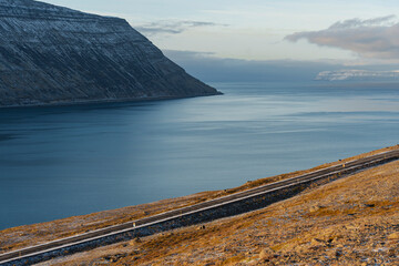 Scenic coastal road winding along the serene waters of a majestic fjord.
