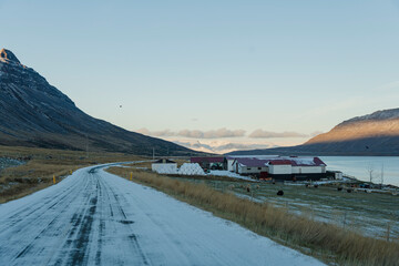 Winding road cutting through winter landscape with mountains and farmlands.