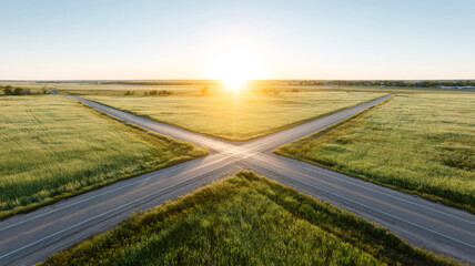 Two country roads intersecting in a lush green field at sunrise, creating a cross shape. Aerial view highlighting decision and future