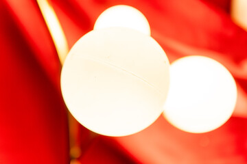 A soft-focus, abstract shot of warm, bright globe lights against a rich red curtain backdrop, creating an elegant and vibrant mood.
