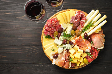 Antipasto platter with wine. Cheese and meat - jamon, salami with olives at wooden table. Top view with copy space.