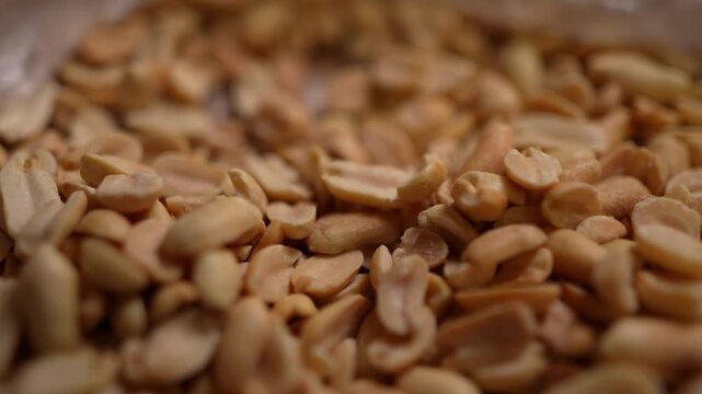 Spicy flavored peanut kernel spilling on white table background.