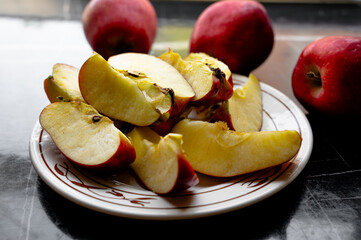 Fresh red apples cut into slices and served on a plate placed on a table.