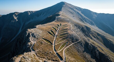 Aerial view mountains with scenic hiking trails winding up peak. Mountains paths create leaf-like pattern and invite exploration, perfect for outdoor adventures and human connection to nature.
