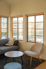 Sunlit corner of a cozy living room featuring a sofa, chair, and round table.