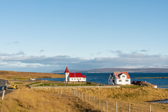 Scenic landscape with a white church and houses near a lake in Iceland.