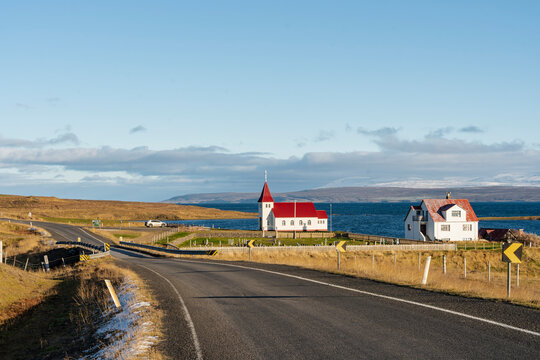 Picturesque Icelandic countryside road leading to a church by the water.