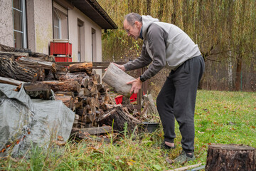 dorosła osoba układająca przy domu drewno na opał