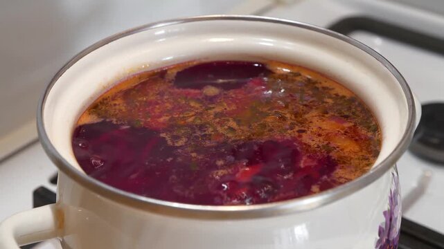 Red Ukrainian borscht is boiling in saucepan. National dish of Ukraine. Main first course of Ukrainian cuisine. Ukrainian borscht is cooked on gas stove. Cooking first courses