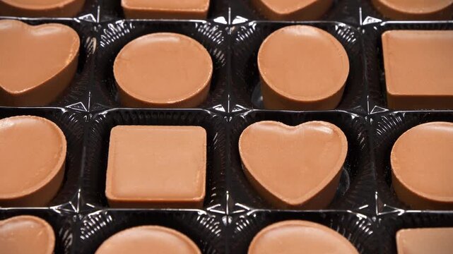 Valentines Day Gift. Candies are round, square and heart-shaped. Chocolate candies in a packaging. Delicious chocolate candy with of different forms, including heart-shaped ones