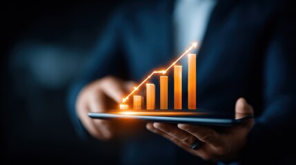 Digital business growth concept with a professional holding a tablet displaying an illuminated ascending bar graph for success.