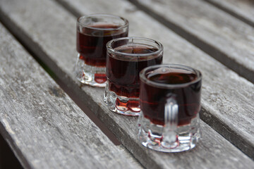 Three small glasses with alcohol made of sweet berries