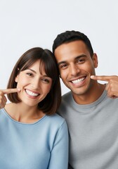 Smiling young diverse couple happily pointing at their perfect, healthy white teeth, showcasing their bright and confident dental health and joy