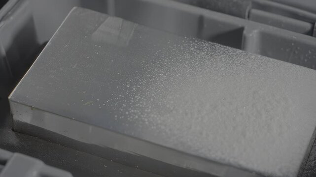 Close-up of a speckled grey block in a plastic organizer, textured surface