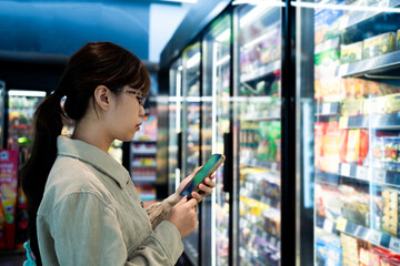 A woman is looking at her phone in a grocery store