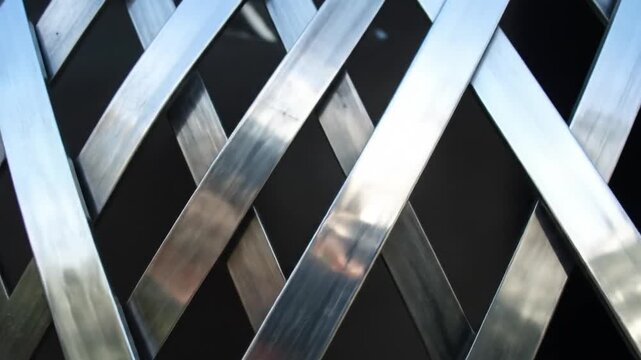 Metallic, crisscrossing strips of a reflective material create a woven pattern against a dark background