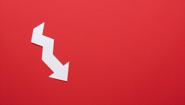 Closeup of a zigzag paper arrow on a red backdrop, suitable for text layout